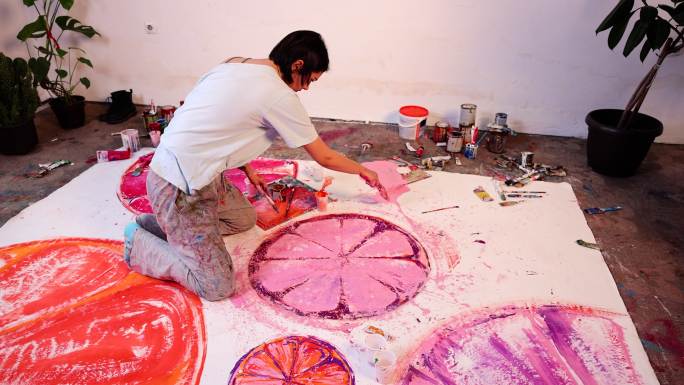 工作室中的高加索女艺术家在大画布上绘画