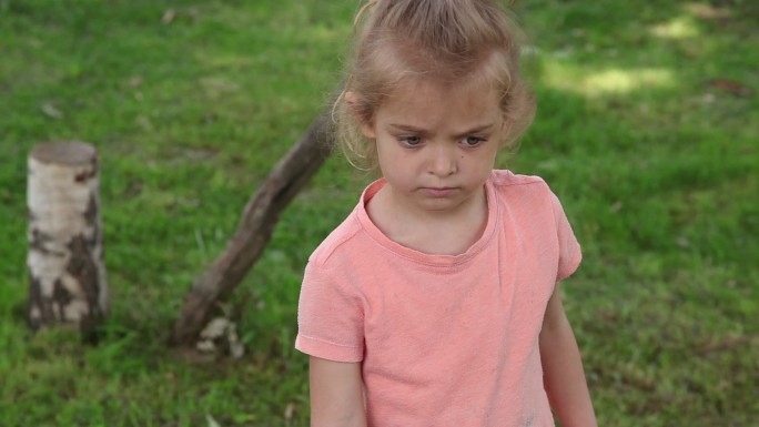 悲伤的小女孩站在公园里