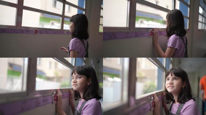 沉思的女孩在学校透过窗户看