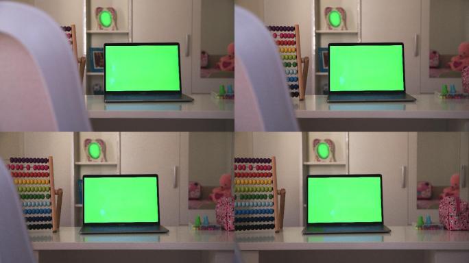 学校用品。儿童房桌子上的笔记本电脑显示绿色彩色按键屏幕的场景。技术背景概念