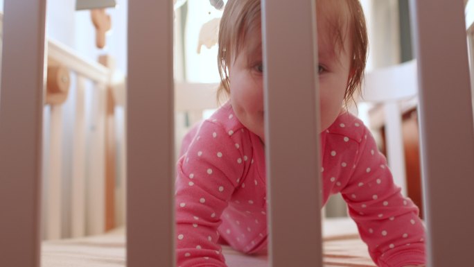 阳光明媚的早晨，穿着粉色紧身衣的可爱快乐女婴在室内玩得很开心