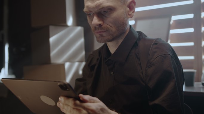一位严肃的中年男子在数字平板电脑的屏幕上阅读文本