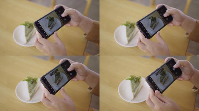 咖啡馆桌上的绿茶蛋糕和手用手机拍照