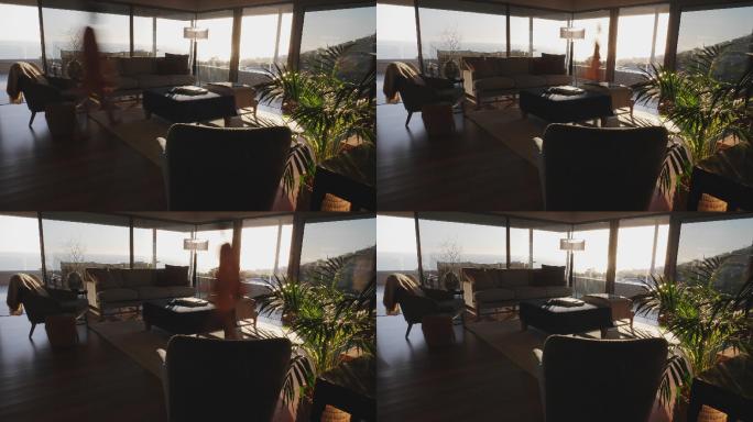 模糊的女人走在阳光明媚的豪华客厅，欣赏海景