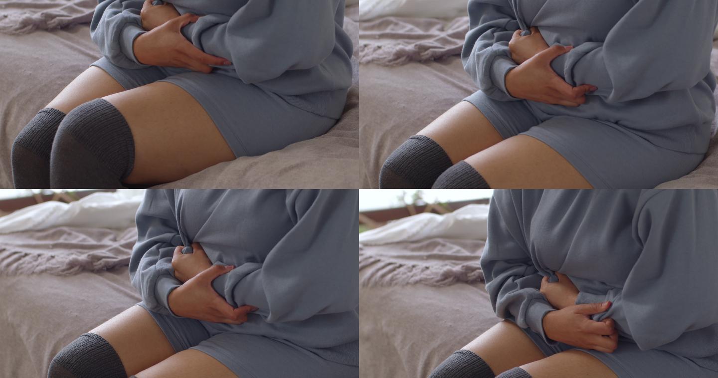 4k视频片段，一名无法辨认的女子在家躺在床上时胃痛