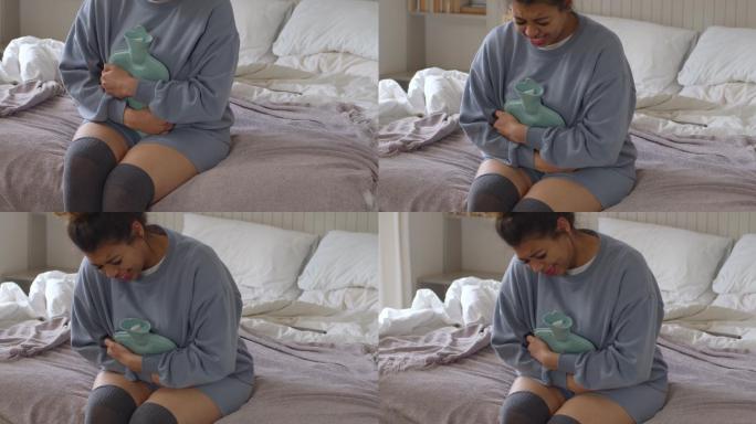 一名年轻女子坐在家中的床上，胃痛的4k视频片段