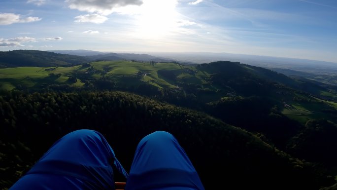 双腿可见的滑翔伞飞行期间的山脉鸟瞰图