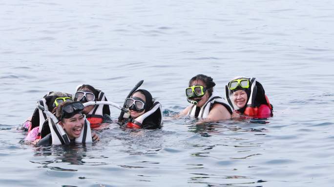 亚洲人在海里浮潜穿救生衣在海上玩耍一群女