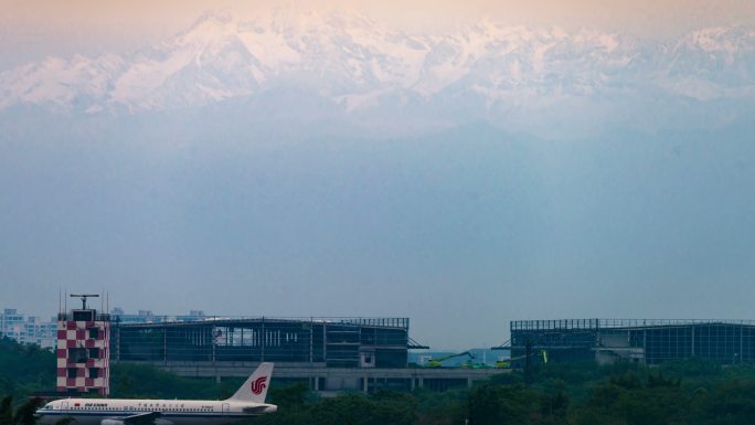 清晨雪山下成都双流国际机场飞机起飞
