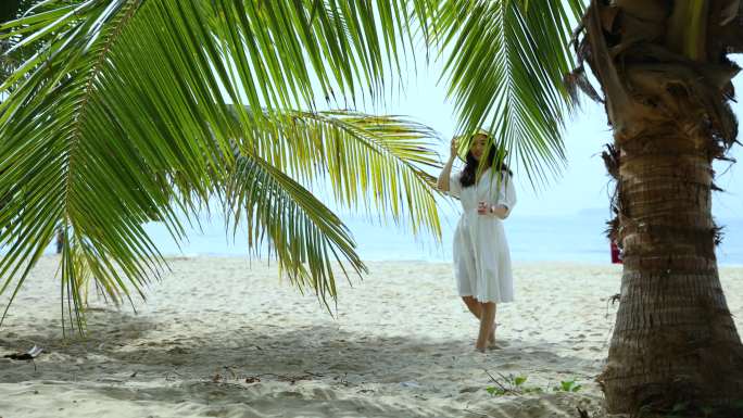 海滩上椰子树下散步的女人