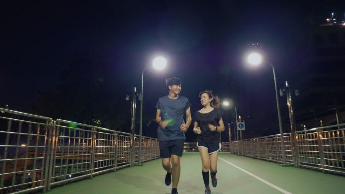 亚洲情侣在城市之夜跑步