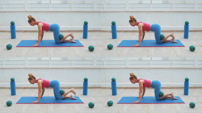 健身女子在运动垫上用球踢驴子侧踢