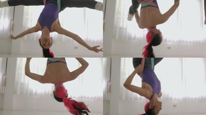 泰国活跃的年轻女子在做反重力瑜伽练习时倒挂着，用丝绸吊床支撑着-库存视频