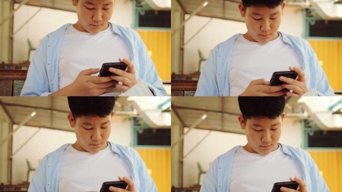 坐在百货公司玩手机游戏的亚洲男孩，ifestyle concept。