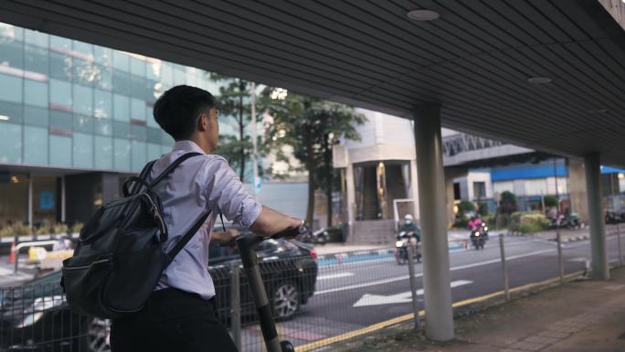 亚裔华裔商务人士骑电动推式踏板车进城工作