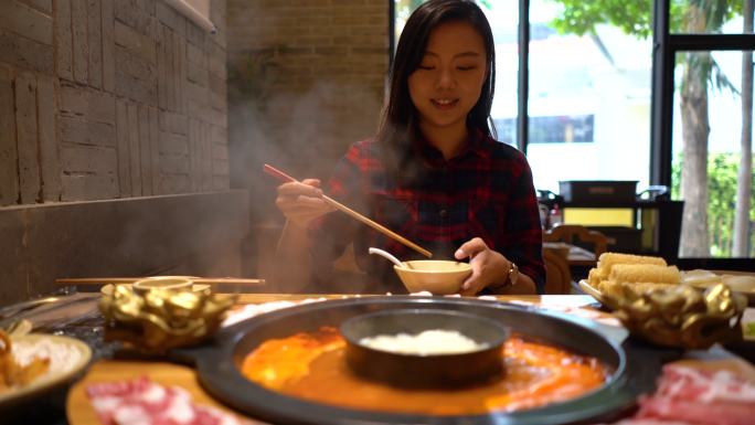 亚洲年轻女子在餐厅享用中国火锅