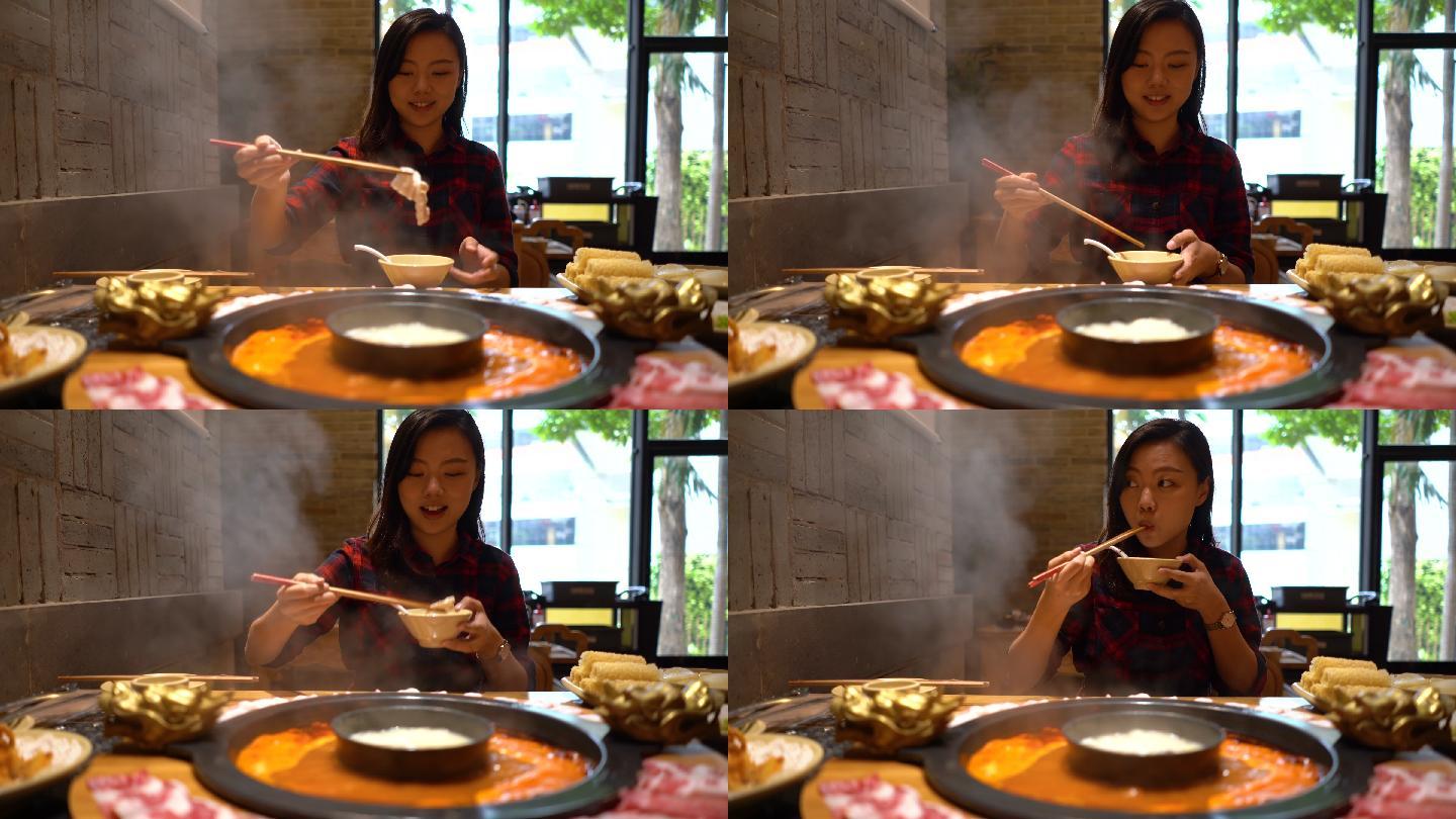 亚洲年轻女子在餐厅享用中国火锅