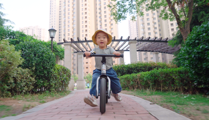 小男孩骑着单车在小区里玩耍