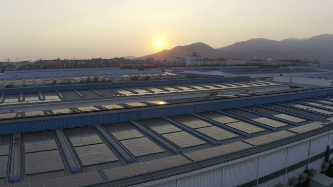 日落时分安装在一家大型工厂屋顶上的太阳能电池板鸟瞰图