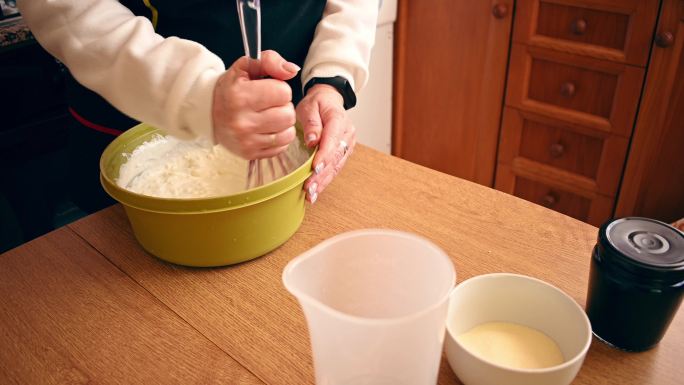 一个女人在碗里搅拌奶油制作奶酪蛋糕的特写镜头