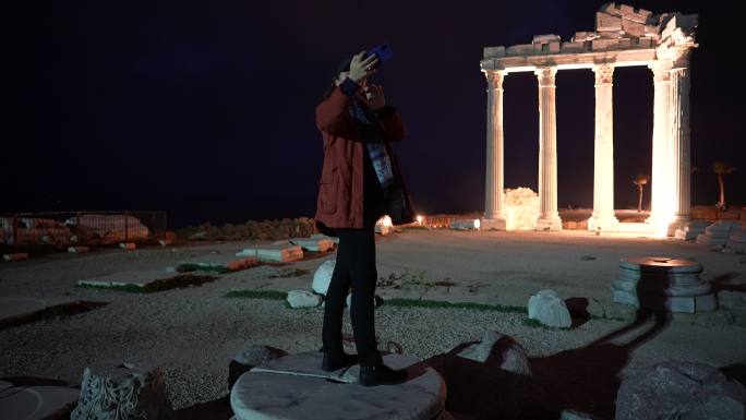 土耳其安塔利亚，夜间在阿波罗神庙一侧拍照的女性游客
