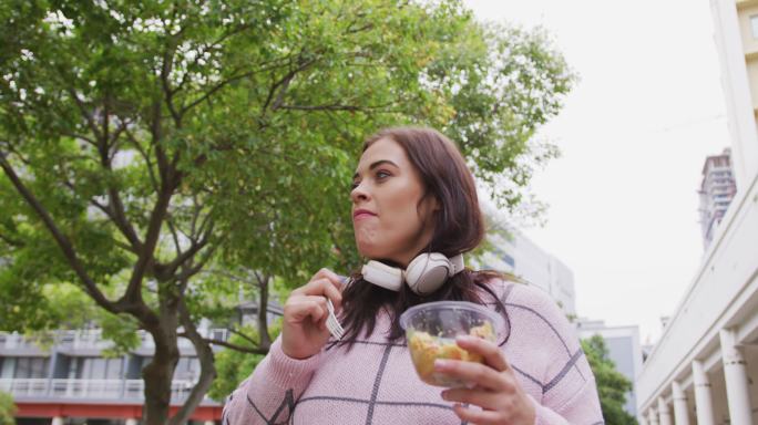 年轻的白人女人边吃边走