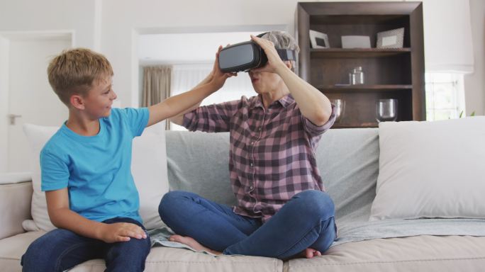 戴着虚拟现实头盔的老妇人和她的孙子
