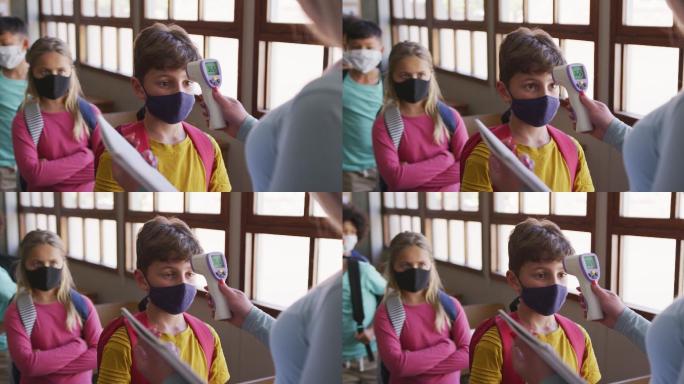 男孩戴着口罩在学校的课堂上测量体温