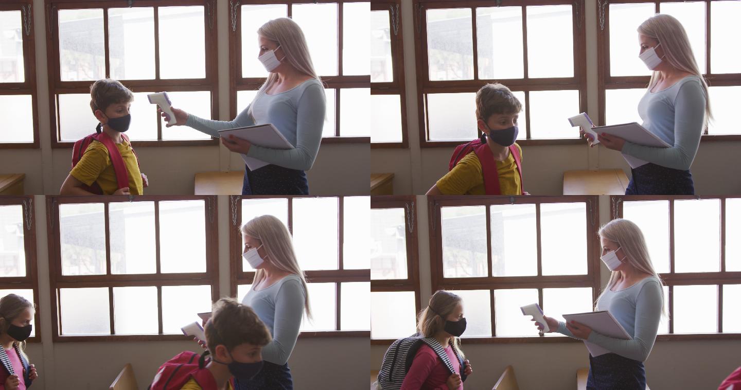 女老师戴着口罩在学校测量一个男生上课的温度