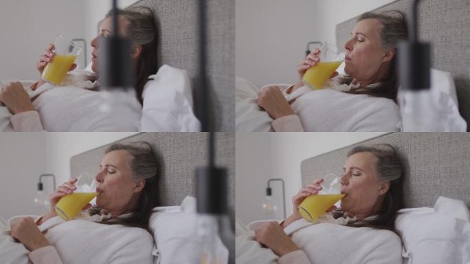 生病的女人躺在家里的床上喝果汁