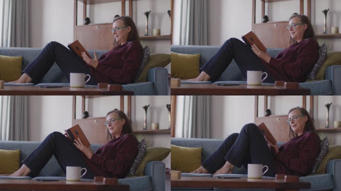 一个女人坐在家里的沙发上看书