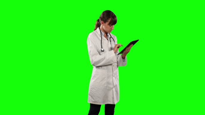 一位女医生使用绿色屏幕的数字平板电脑的侧视图