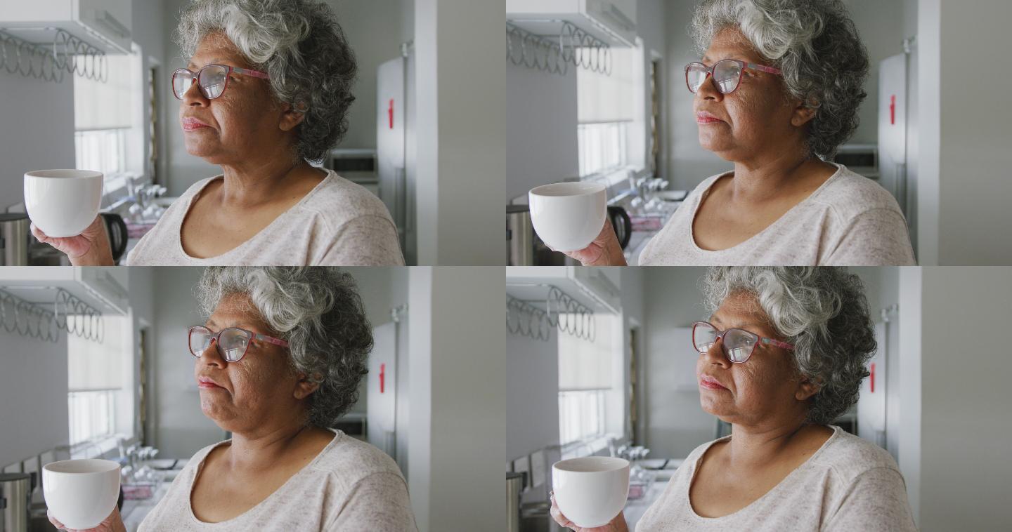 一个年长的非裔美国妇女在家里拿着一个杯子。隔离期间的社交距离