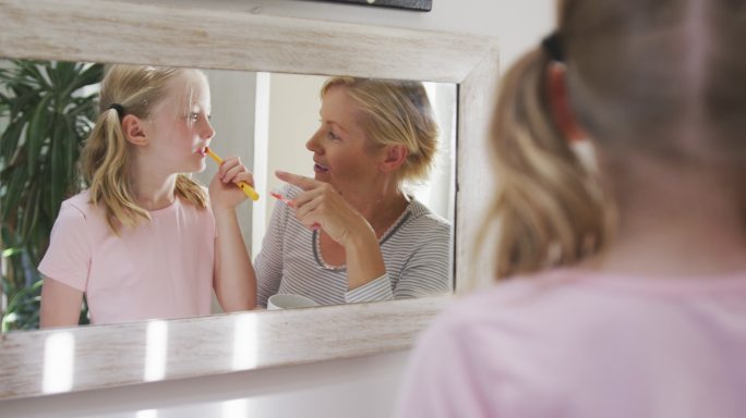 身后是一个白人女人和她的女儿在刷牙