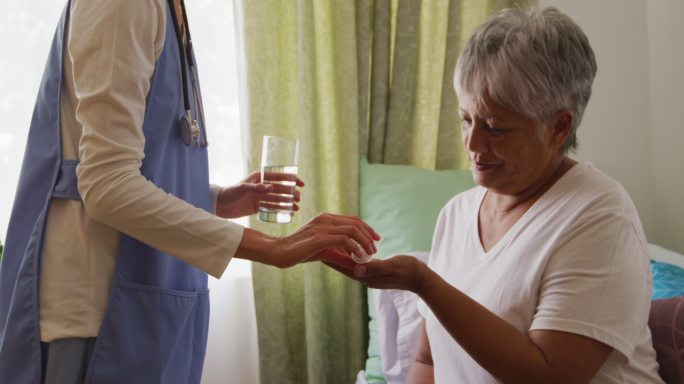 在养老院帮助一位老年妇女的护士