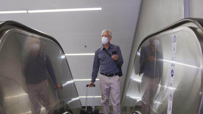 一名白人男子戴着抗击冠状病毒的面罩在地铁站内走动