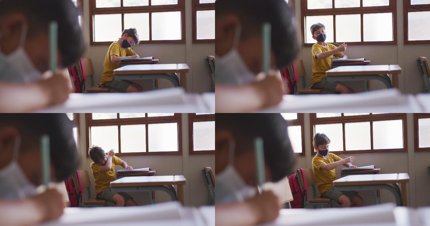 男孩戴着口罩，坐在课桌上打喷嚏