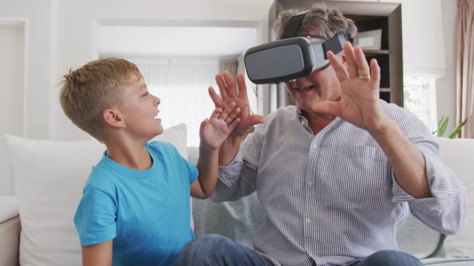 一位戴着虚拟现实头盔的老人和她的孙子在一起