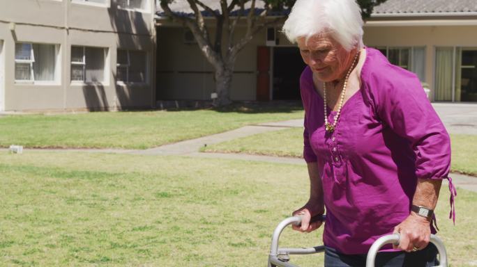 一位老妇人在养老院的公园里散步