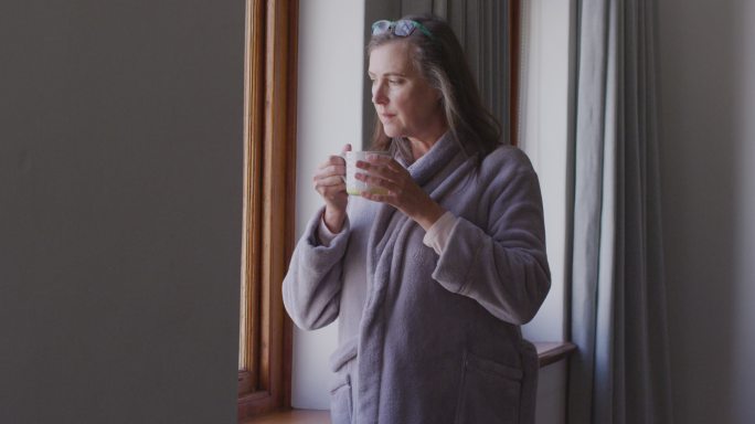 在家里一边喝咖啡一边看窗外的女人
