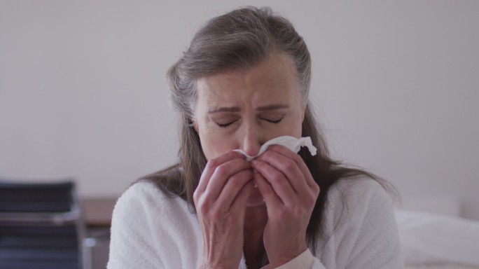 生病的女人在家里用纸巾打喷嚏