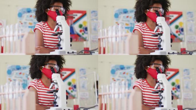 女孩戴着口罩和防护眼镜在实验室使用显微镜