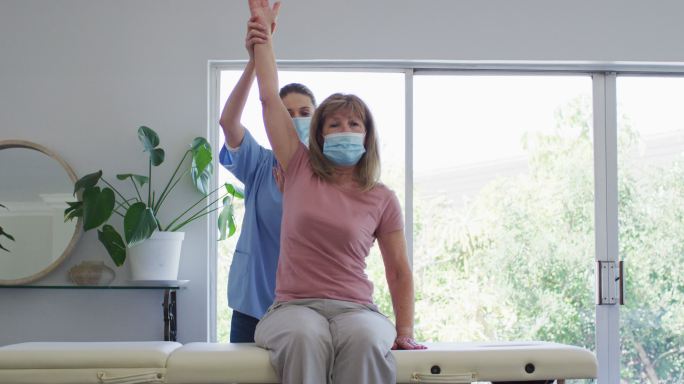 女性卫生工作者在家中伸展老年妇女的手臂