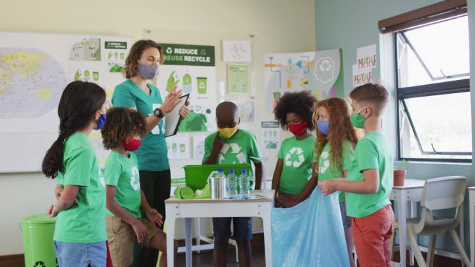 一群戴着口罩将塑料物品放入回收容器的孩子