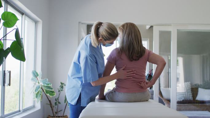 女性卫生工作者在家中伸展年长妇女的背部