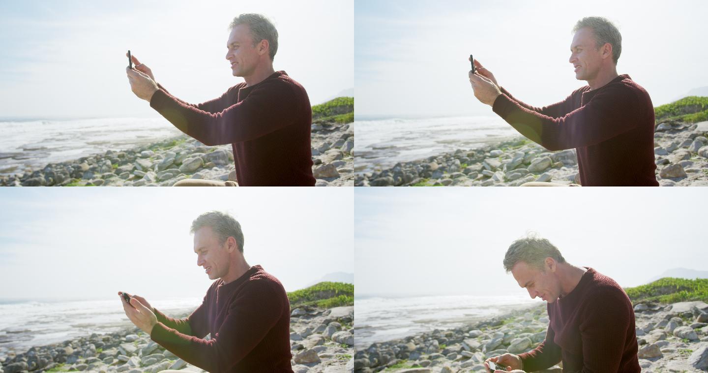 一名白人男子在阳光明媚的日子里坐在智能手机上享受海上的自由时光