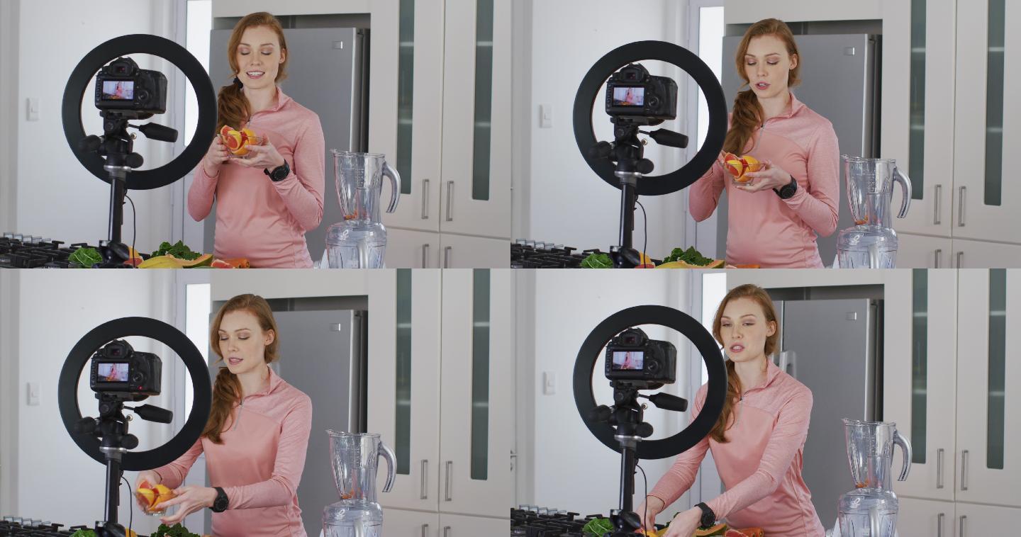 一个女人拿着一碗切好的水果，在厨房用数码相机记录下