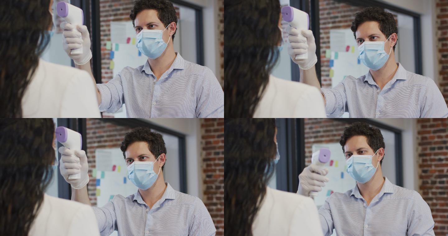 一名戴面罩的男子在办公室为一名女子检查体温