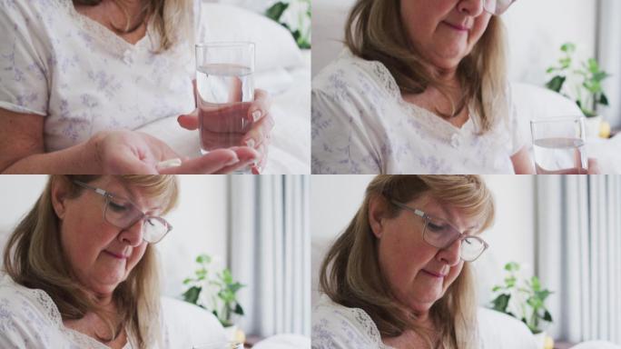 Senior woman holding pills and glass of water at h