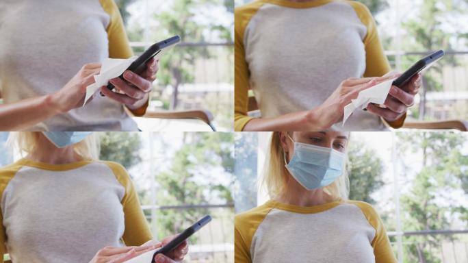 戴口罩的女子用纸巾擦拭智能手机